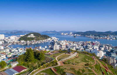 High angle view of city by sea and buildings against sky