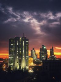 Illuminated buildings in city against sky during sunset
