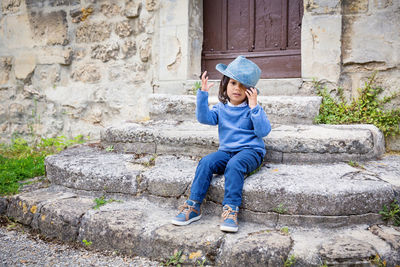 Little handsome baby boy sitting on ancient stone stairs