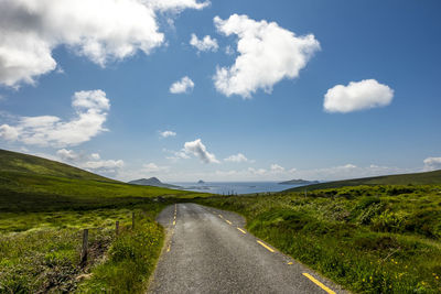 Road amidst field against sky