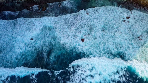 Texture dark ocean waves with white foam. drone filming breaking surf in indian ocean, nusa penida