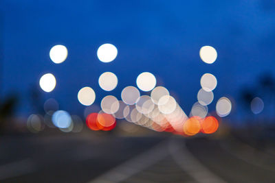 Defocused image of illuminated lights against sky