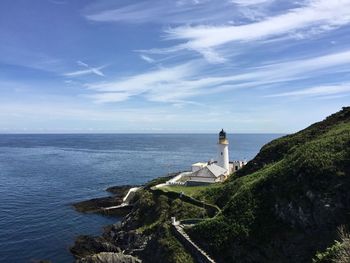 Lighthouse by sea against sky