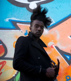 Portrait of young man against graffiti wall