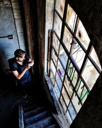 High angle portrait of woman sitting on window