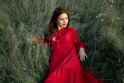 Portrait of young woman standing against plants