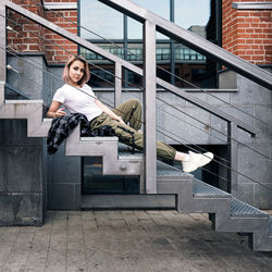 Hip hop style girl with a dslr camera  laying on metal stairs in an urban environment