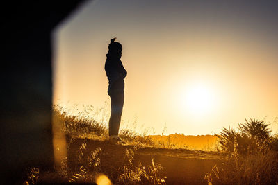 Silhouette man standing on field against sky during sunset