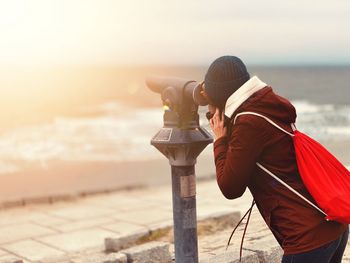 Woman looking through coin-operated binoculars at beach