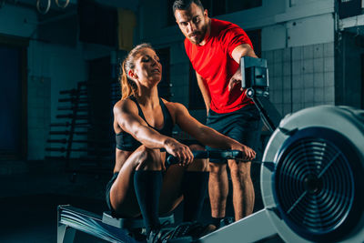 Coach instructing woman exercising at gym