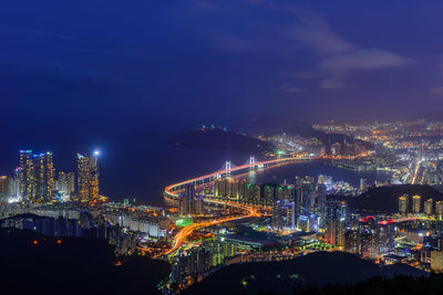 Illuminated modern buildings in city against sky at night