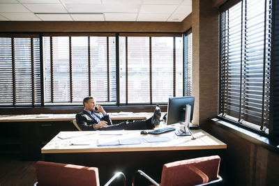 Businessman talking on mobile phone while relaxing in office