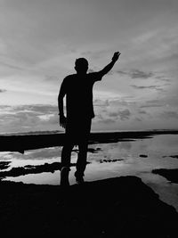 Silhouette man standing by sea against sky