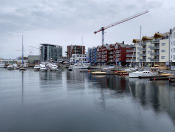 Sailboats moored on island by buildings in city against sky
