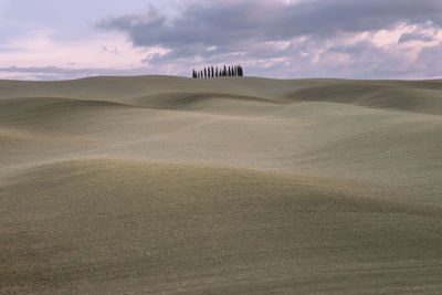 Scenic view of desert against cloudy sky