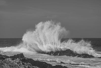 Waves splashing on shore against sky