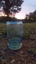 Close-up of water on field against sky at sunset