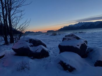 Scenic view of snow covered land against sky during sunset