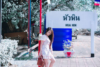 Portrait of smiling young woman standing against plants