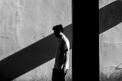 Side view of a man with umbrella walking on wall