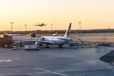 Airplane on runway against sky during sunset