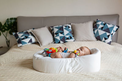 Midsection of baby lying on sofa at home