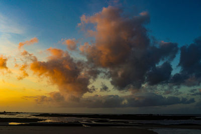 Scenic view of sea against dramatic sky during sunset