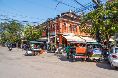 Cars on city street by buildings against sky