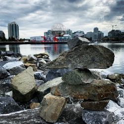 Rocks by river against buildings in city