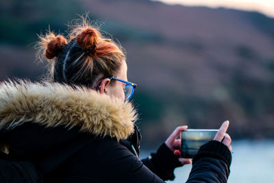 Side view of woman photographing through smart phone