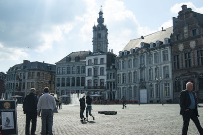 People on buildings in city against sky