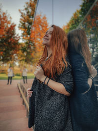 Smiling young woman standing against building