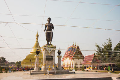 Low angle view of statue against buildings in city against sky