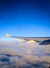 Airplane flying over clouds against blue sky