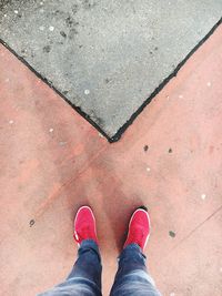 Low section of man wearing red shoes standing on footpath