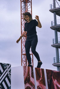 Full length portrait of young woman standing against ladder