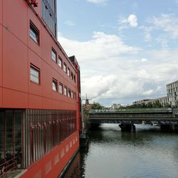 Bridge over river by buildings in city against sky