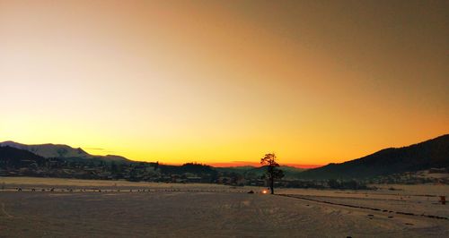 Silhouette person standing on field against sky during sunset