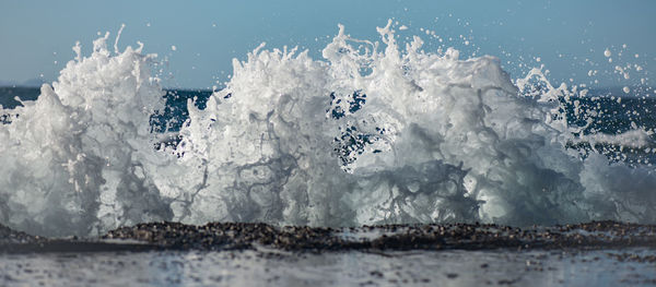 Panoramic view of waves splashing on shore