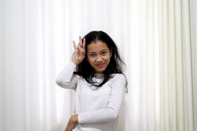 Portrait of smiling woman standing against wall