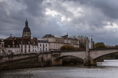 Bridge over river in city against sky