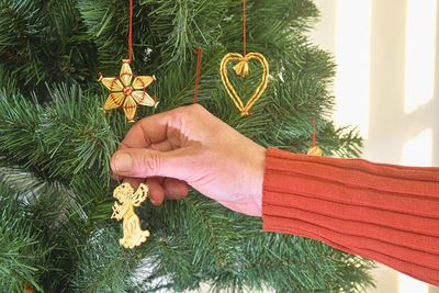 Decorating christmas tree, hand putting christmas decorations on branches. christmas hanging
