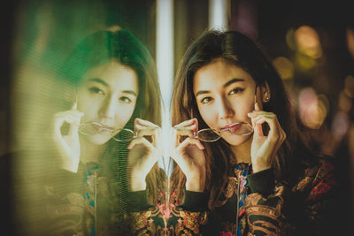 Portrait of young woman by window with reflection