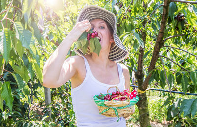 Portrait of senior woman holding strawberry against plants