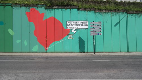 Information sign on road against wall in city