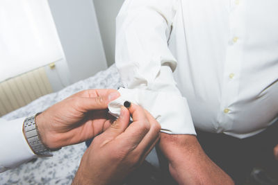 Cropped hand attaching cuff link to shirts cuff