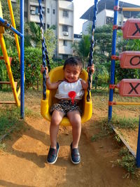 Smiling girl sitting on swing in playground