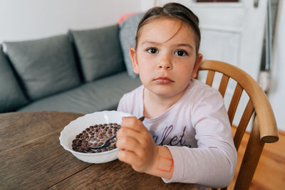 Portrait of cute baby girl eating food at home