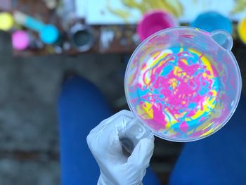 Close-up of hand holding multi colored liquid in container