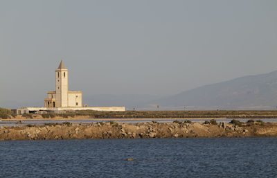 Church building by sea against clear sky in cabo de gata nature park, almeria, spain